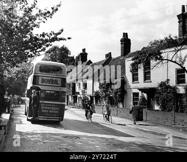 Straßenszene in einem kleinen ruhigen englischen Dorf , Sonning on Thames , Berkshire , England . Einheimische warten an der Bushaltestelle und andere radeln die Straße hinunter. 1946 Stockfoto