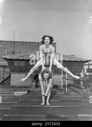 „Over the Rainbow“ dieses „Frühlingsgefühl“, das von den Windmill Girls Josephine Hamlett und Jaqueline Rainbow zum Ausdruck gebracht wird, während sie eine Pause bei den Proben einlegen, um das Sommerwetter auf dem Dach des berühmten Londoner Non-Stop-Theaters zu genießen. Josephine springt über „Jacky“ Rainbow. März 1948 Stockfoto