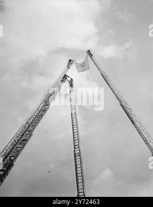 Mit der Übergabe an die örtliche Kontrolle aller Stationen und Geräte der nationalen Feuerwehr heute (Montag) nahm der Sicherheitsbeamte J Chuter Ede an einer Zeremonie im NFS-Hauptquartier in London Teil, um die offizielle Übergabe zu feiern. In einer Botschaft an die NSS-Mitglieder würdigt Herr Ede die Pflichtverehrung der Männer und Frauen des Dienstes. Das Bild zeigt: Hochpass der Boden trägt die NSS-Flagge, während Mitglieder der London Brigades die Agilität auf Feuerflüchten nach der heutigen Zeremonie im Hauptquartier in London demonstrieren. April 1948 Stockfoto