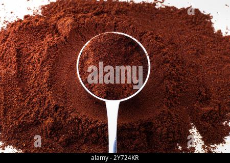 Löffel in braunem Kaffeepulver. Isoliert auf weiß. Perfekt als Hintergrundbild. Leeres Leerzeichen für Text. Stockfoto