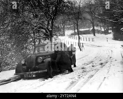 Schneestürme haben dieses Wochenende über Großbritannien gehegt, und Südostengland war der schlimmste Hit. Viele Straßen in der Gegend von Surrey und Kent waren aufgrund des starken Schneefalls unpassierbar. Das Bild zeigt: Einem Autofahrer wird geholfen, als er auf dem Warlington-Westerham Hill in Surrey in Schwierigkeiten geriet. 3. März 1946 Stockfoto