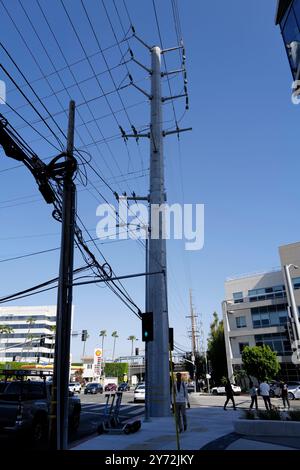 : Fotos mit Stromleitungen, Straßenecken und Autos mit klarem blauem Himmel und städtischer Infrastruktur im Hintergrund. Stockfoto