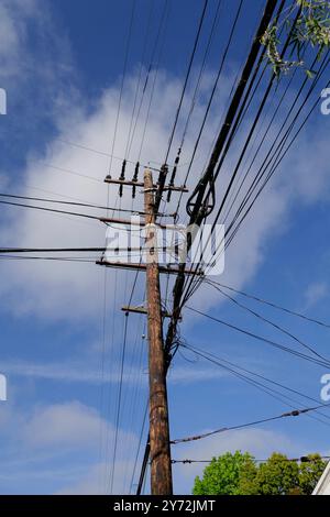 : Fotos mit Stromleitungen, Straßenecken und Autos mit klarem blauem Himmel und städtischer Infrastruktur im Hintergrund. Stockfoto