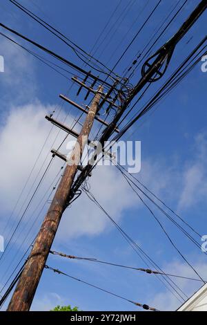 : Fotos mit Stromleitungen, Straßenecken und Autos mit klarem blauem Himmel und städtischer Infrastruktur im Hintergrund. Stockfoto