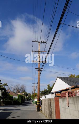 : Fotos mit Stromleitungen, Straßenecken und Autos mit klarem blauem Himmel und städtischer Infrastruktur im Hintergrund. Stockfoto