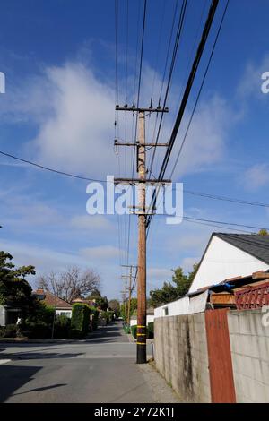 : Fotos mit Stromleitungen, Straßenecken und Autos mit klarem blauem Himmel und städtischer Infrastruktur im Hintergrund. Stockfoto