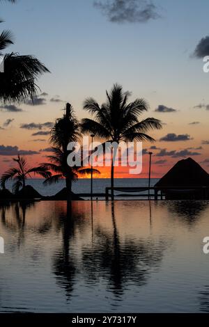 Sonnenaufgang über dem Golf von Mexiko spiegelt sich in den Infinity-Pool im Resort Stockfoto