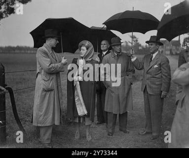 Die Delegierten der Internationalen Konferenz der landwirtschaftlichen Erzeuger wurden von seiner Majestät dem König in Windsor auf der Royal Farm empfangen. Später besuchen die Teilnehmer die 10 englischen Bauernländer und besuchen jeden Tag einzelne Farmen. Das Bild zeigt den König und die Königin während der Tour durch die königliche Farm - ein plötzlicher Regenguss verursachte einen Sturm nach Regenschirmen, unterbrach aber nicht das Programm. 18. Mai 1946 Stockfoto