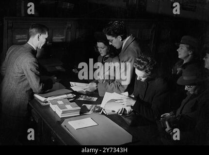 Kunden, die Kataloge mit Agenten der Reiseagentur Thomas Cook, London.1946, durchsehen Stockfoto