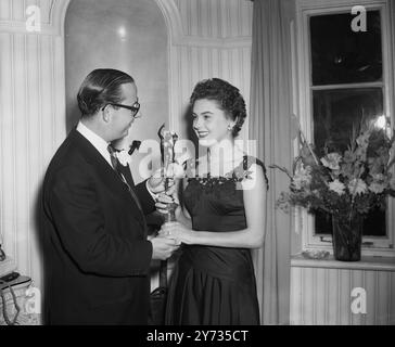 Der Schuhmacher der Königin ( Edward Rayne ) kaufte ein Haus von der Schneiderin der Königin ( Norman Hartnell ) Und bei der Einweihungsparty im Tower House, Park Village Walk, Albany Street, London. Jill Clifford überreicht Edward Rayne am 29. August 1952 ein Einweihungsgeschenk Stockfoto