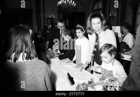 Prinzessin Grace von Monaco, unterstützt von ihren drei kleinen Kindern Prinzessin Stephanie (rechts) und Prinzessin Caroline, Prinz Albert und Prinz Rainier (Hintergrund), überreicht Weihnachtsgeschenke an Kinder bei einer Weihnachtsfeier im Grimaldi-Palast in Monaco am 21. Dezember 1967 Stockfoto