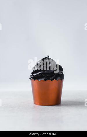 Orange Cupcakes mit schwarzem Buttercremewirl, Cupcakes in orangefarbenen Folieneinlagen mit schwarzer Buttercreme, Frosted Halloween Cupcakes auf weißem Hintergrund Stockfoto