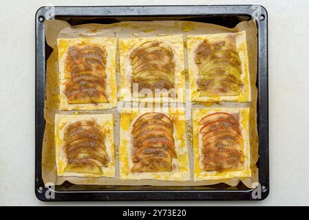 Frisch zubereitetes Apfelgebäck mit Zimt auf einem mit Backpapier ausgelegten Blech. Blick von oben, Hausgebacken, rustikaler Stil. Konzept der hausgemachten de Stockfoto