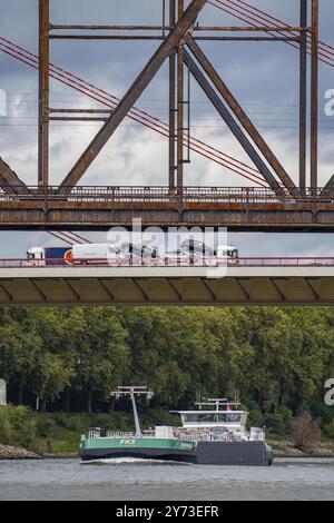 Die Rheinbrücke Beeckerwerth der Autobahn A42, Lkw-Verkehr, davor die Haus-Knipp Eisenbahnbrücke, Güterschiff auf dem Rhein bei Duisburg Stockfoto