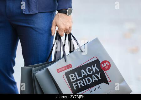 Junger Mann mit Einkaufstaschen auf der Stadtstraße, Nahaufnahme. Black Friday-Angebot Stockfoto