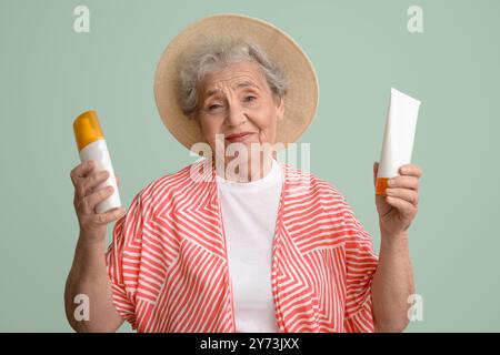 Seniorin mit Sonnencreme auf grünem Hintergrund Stockfoto