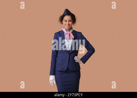 Wunderschöne afroamerikanische Stewardess auf beigefarbenem Hintergrund Stockfoto