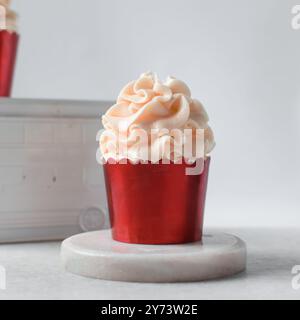 Rote Cupcakes mit rosafarbenem Buttercremewirl, Cupcakes in roter Folienfolie mit rosafarbener Buttercreme Stockfoto