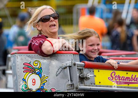 Saint John, Kanada - 22. Juni 2024: Eine Mutter und Tochter reiten auf dem Scrambler. Die Frau trägt eine Sonnenbrille. Beide scheinen sich zu amüsieren. Stockfoto