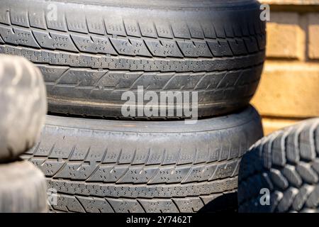 Verschlissene und beschädigte Lauffläche alter Reifen, die auf einer Deponie liegen. Verringerung der Straßenverkehrssicherheit und der Umweltverschmutzung durch Gummiabfälle Stockfoto