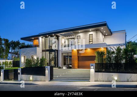 Modernes Luxushaus mit großen Fenstern, Gartenanlage und Abendbeleuchtung. Stockfoto
