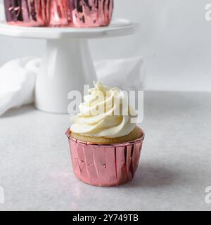 Rosafarbene Cupcakes mit hohem Buttercremewirl, Cupcakes in rosafarbenen Folieneinlagen mit Vanille-Buttercreme, mattierte Cupcakes auf weißem Hintergrund Stockfoto