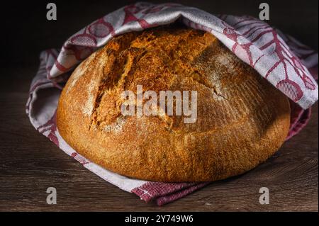 Traditionelles Sauerteig-Brot mit roughiger Schale auf einem rustikalen Holztisch. Fotos von gesunden Lebensmitteln Stockfoto