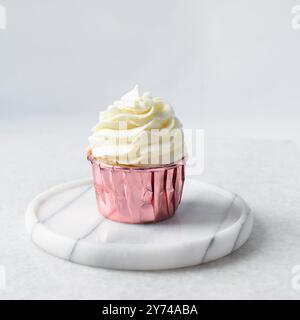 Rosafarbene Cupcakes mit hohem Buttercremewirl, Cupcakes in rosafarbenen Folieneinlagen mit Vanille-Buttercreme, mattierte Cupcakes auf weißem Hintergrund Stockfoto