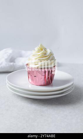 Rosafarbene Cupcakes mit hohem Buttercremewirl, Cupcakes in rosafarbenen Folieneinlagen mit Vanille-Buttercreme, mattierte Cupcakes auf weißem Hintergrund Stockfoto