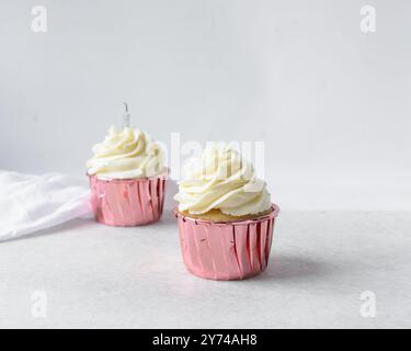 Rosafarbene Cupcakes mit hohem Buttercremewirl, Cupcakes in rosafarbenen Folieneinlagen mit Vanille-Buttercreme, mattierte Cupcakes auf weißem Hintergrund Stockfoto