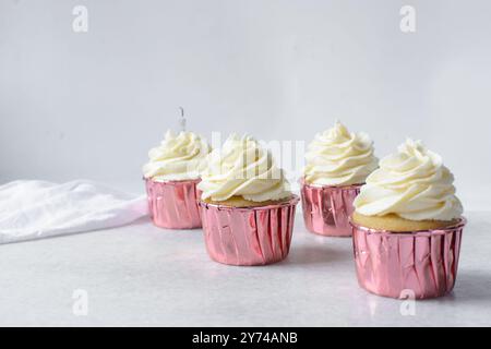 Rosafarbene Cupcakes mit hohem Buttercremewirl, Cupcakes in rosafarbenen Folieneinlagen mit Vanille-Buttercreme, mattierte Cupcakes auf weißem Hintergrund Stockfoto