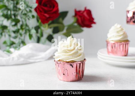 Rosafarbene Cupcakes mit hohem Buttercremewirl, Cupcakes in rosafarbenen Folieneinlagen mit Vanille-Buttercreme, mattierte Cupcakes auf weißem Hintergrund Stockfoto