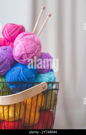 Viele bunte Garne zum Stricken und Häkeln in einem stilvollen Korb im scandi-Stil. Stockfoto