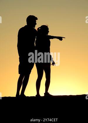 Eine Reihe von fesselnden Silhouetten, die ein Paar mit zarten Momenten bei Sonnenuntergang zeigt und eine ruhige und romantische Atmosphäre schafft. Stockfoto