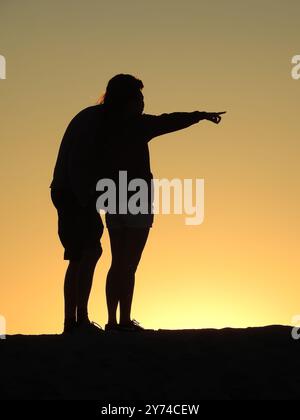 Eine Reihe von fesselnden Silhouetten, die ein Paar mit zarten Momenten bei Sonnenuntergang zeigt und eine ruhige und romantische Atmosphäre schafft. Stockfoto