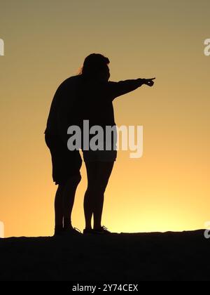 Eine Reihe von fesselnden Silhouetten, die ein Paar mit zarten Momenten bei Sonnenuntergang zeigt und eine ruhige und romantische Atmosphäre schafft. Stockfoto