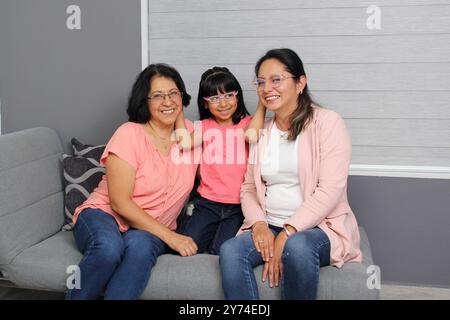 Drei Generationen von Frauen, Großmutter, Mutter und brünette Latina Tochter mit Brille zeigen ihre Liebe und feiern Muttertag Stockfoto