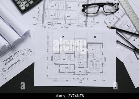 Verschiedene Architekturzeichnungen, Lineal, Trennwand und Bleistift auf grauem, strukturiertem Tisch, flache Lagen Stockfoto