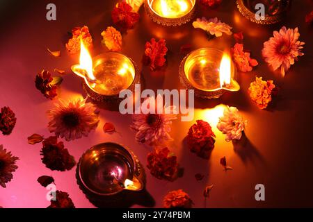 Diwali-Feier. Diya-Lampen und wunderschöne Blumen auf farbigem Hintergrund, über dem Blick Stockfoto