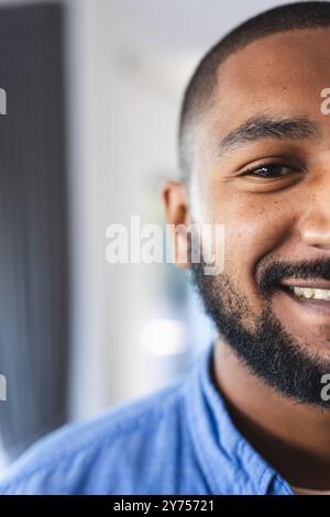 Ein lächelnder Mann in blauem Hemd genießt die Zeit mit verschiedenen Freunden drinnen, im Kopierraum, zu Hause Stockfoto