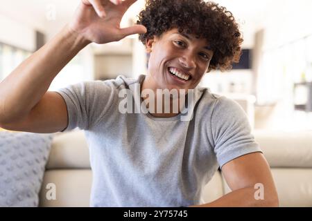 Auf Videoanruf, lächelnder junger Mann, der die Hand winkt, die Zeit drinnen, zu Hause genießt Stockfoto