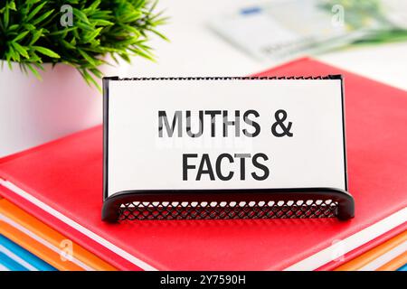 Business, Finanzen und Fakten im Vergleich zum Mythos. Symbol für Fakten und Mythen. Konzeptwörter Fakten und Mythen auf einer Visitenkarte, die auf einem Ständer auf Notizbüchern steht Stockfoto
