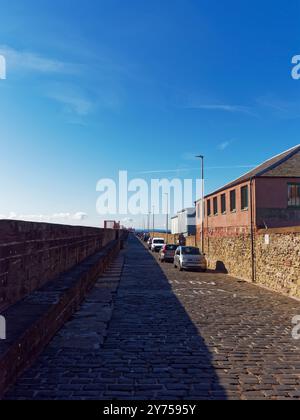 Blick auf den inneren Kai des Arbroath Breakwater, mit geparkten Autos neben Mackays Shipbuilders im Inner Harbour selbst. Stockfoto