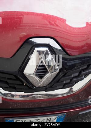 Cremona, Italien 26. September 2024 Nahaufnahme eines renault-Logos auf der Vorderseite eines roten Autos, mit der Reflexion der Straße in Chrom Stockfoto