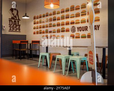 Cremona, Italien 26. September 2024 leeres Interieur eines modernen Fast-Food-Restaurants mit orangefarbenen und grünen Metallstühlen und Holztischen Stockfoto