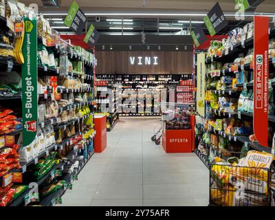 Cremona, Italien 26. September 2024 Ein moderner Supermarktgang mit einem Einkaufswagen, der zwischen Regalen mit verschiedenen Waren steht Stockfoto