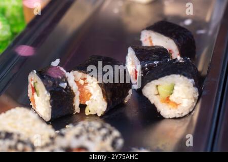 Dieses Bild zeigt eine Nahaufnahme einer Auswahl an farbenfrohen Sushi-Rollen, die elegant auf einem dekorativen Tablett angeordnet sind und deren Attraktivität zum Ausdruck bringen Stockfoto