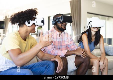 Mithilfe von VR-Headsets genießen verschiedene Freunde gemeinsam das Virtual-Reality-Erlebnis drinnen und zu Hause Stockfoto