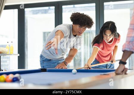 Billard spielen, verschiedene Freunde zielen und konzentrieren sich auf Billardtisch während des Treffens, zu Hause Stockfoto