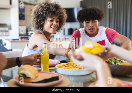 Verschiedene Freunde genießen gemeinsam Essen und greifen zu Hause nach Essen und Getränken am Tisch Stockfoto